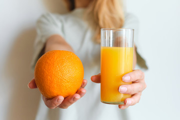 Girl holds a glass of orange juice in her hands. Fresh natural orange juice. Vitamin drink for breakfast. Healthy lifestyle, organic diet. Refreshment after morning fitness. Enjoy delicious beverage