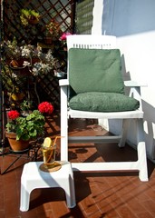 Balcone urbano in una giornata di sole con sedia relax fiori e drink