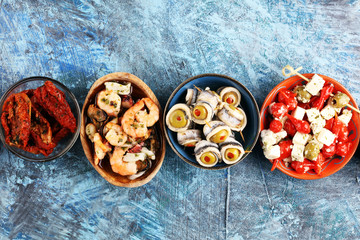Antipasti Appetizer sweet cherry peppers stuffed with soft cheese feta, olives with oil. Seafood and anchovies with olives and dried tomatoes in oil