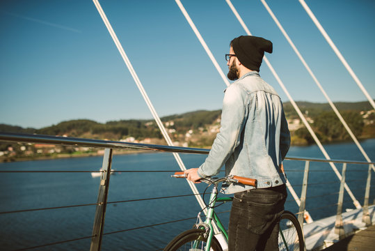 Young man commuting in the city with fis fixie bike, looking at the sea