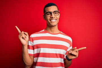 Young handsome african american man wearing casual striped t-shirt and glasses smiling confident pointing with fingers to different directions. Copy space for advertisement