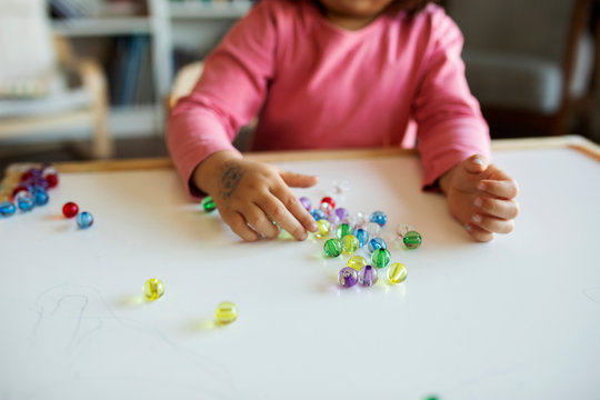 Crop view of girl playing with marbles on table