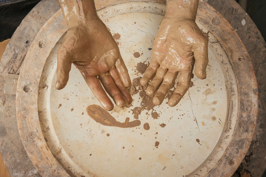 Close-up of muddy hands of a potter in workshop