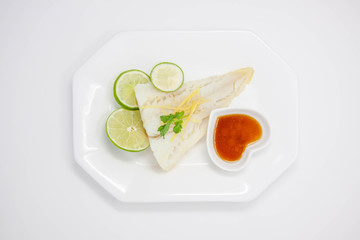 Top view of a plate of fish fillet with green lemon and soya sauce