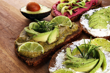 Avocado sandwich. Variation of healthy rye breakfast sandwiches with avocado and toppings like tomato and pomegranate