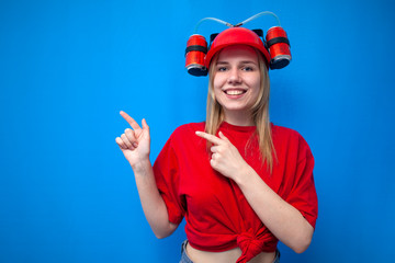 happy funny girl fan in red uniform shows fingers on a place for text and smiles, joyful cheerleader on a blue background