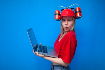 surprised funny girl a fan with a laptop wins online on a blue background, a fan in red uniform and with a beer hat plays on the Internet