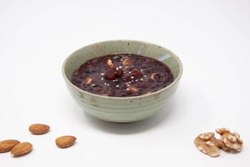 A bowl of purple rice porridge with almond and walnuts