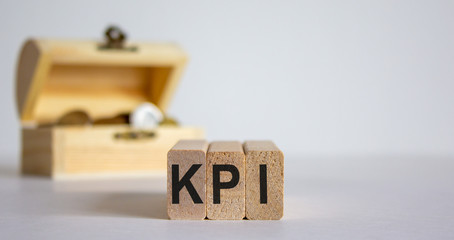 Concept word KPI on cubes on a beautiful white background, small chest with coins.