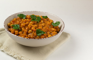 Chana masala in a creamy deep plate on a white background. A traditional dish of Indian cuisine. Copy space.