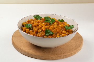 Chana masala in a creamy deep plate on a white background. A traditional dish of Indian cuisine. Copy space.