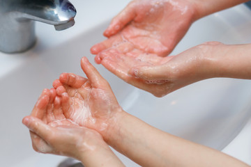 Fototapeta premium Two children, two sisters wash their hands with soap in the sink, protected against viral infection, protection against Covid 19 viruses, healthcare, protection against coronovirus, skin cleansing
