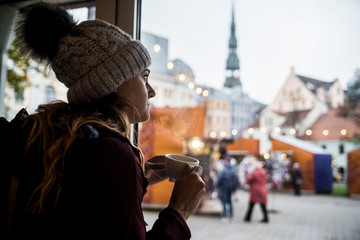 young female traveler enjoying a coffee in cute coffee shop in old town riga latvia