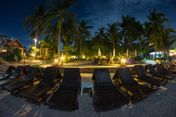 night view from the beach to sun beds and bungalows with illumination