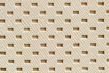 Texture of genuine geometric perforated genuine leather close-up, light cream paint color, background substrate, composition use. With place for your text