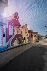Colored unidentified houses along the streets of Costa Nova in the sunshine against a cloudy sky