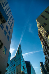 bottom view of colored buildings and sky with traces of aircraft