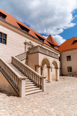 Fototapeta na wymiar renovated castle courtyard with stairs to the balcony with arches and red roof
