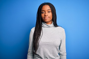 Young african american woman standing wearing casual turtleneck over blue isolated background...