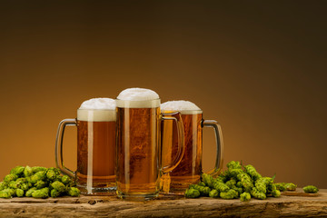 composition with light beer with foam in glasses and hops and wheat on the table, free space for text