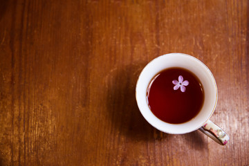 Tea in a mug on an old wooden table. Lilac flower in tea