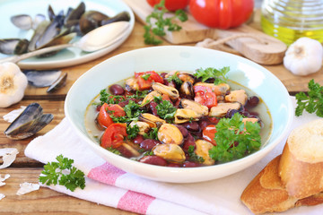 Italian Cuisine.  Soup with mussels, tomatoes and red beans, parsley dressing