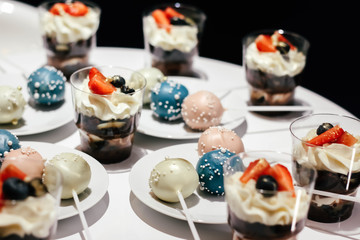 Desserts with whipped cream and strawberries on a white table. Glamorous style