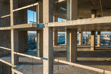 Fototapeta na wymiar Interior of a concrete residential apartment building room with unfinished bare walls and support pillars for future walls under construction.