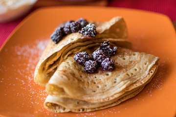 Fresh golden crepes with blackberries made for breakfast