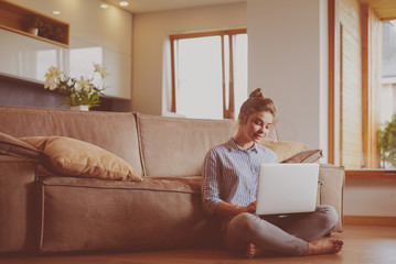 Happy woman with laptop on living room floor