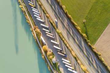 Top down aerial view of highway interstate road with fast moving traffic and parking lot with...