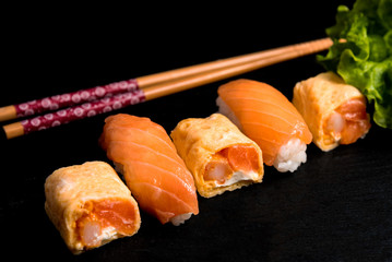 Japanese cuisines nigiri sushi set on black plate served with wasabi, soy sauce. Sushi Roll with salmon, sushi maki roll and tamago sushi on black plate