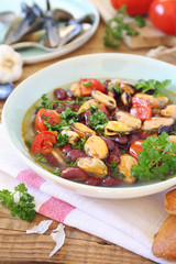 Italian Cuisine.  Soup with mussels, tomatoes and red beans, parsley dressing