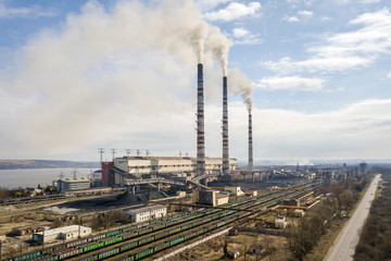 Obraz premium Wysokie rury elektrowni, biały dym na wiejskim krajobrazie, woda w jeziorze i błękitne niebo kopiują tło przestrzeni.