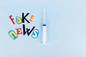 L'insciption Fake news, collage of colored paper's letters, and syringe. The concept of lies in social networks during the world coronavirus pandemic