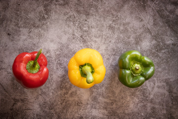 Green, yellow  and Red Bell Peppers on a black cement Background