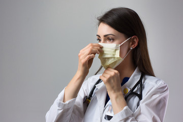 Woman healthcare professional demonstrating proper donning of mask for protection from coronavirus....