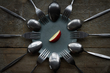 A piece of fruit surrounded by cutlery.