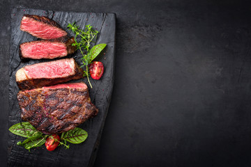 Barbecue dry aged wagyu entrecote beef steak with lettuce and tomatoes as top view on an old...
