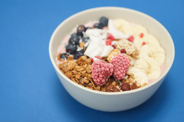 Handmade Bowl healthy tasty breakfast of yogurt, smoothie with granola, nuts, bananas and berries