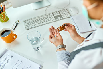 Close-up of businesswoman taking medicine in the office.