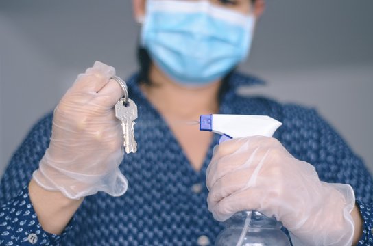 Mujer desinfectando sus llaves mediante aplicaci&oacute;n de aerosol de alcohol para evitar contaminaci&oacute;n por virus, bacterias o enfermedades 