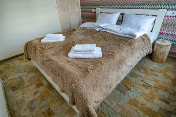 Interior of a spacious hotel bedroom with fresh linen on a big double bed. Cozy contemporary room in a modern house.