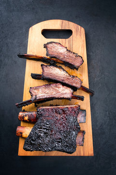Barbecue burnt chuck beef ribs marinated and sliced as top view on a modern design wooden board