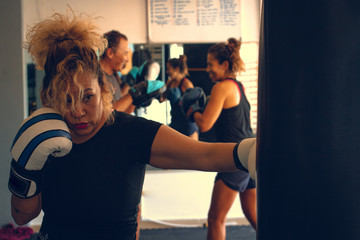 Woman practicing boxing with blue and white gloves in a gym