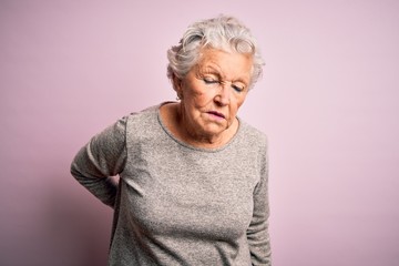 Senior beautiful woman wearing casual t-shirt standing over isolated pink background Suffering of backache, touching back with hand, muscular pain