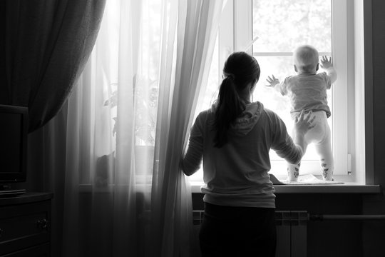 Young Woman With A Child Looking Out The Window