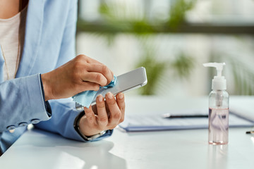 Close-up of businesswoman cleaning her cell phone in the office.
