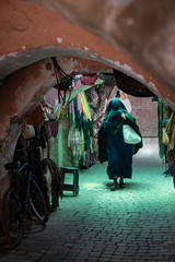 Fototapeta na wymiar Muslim woman walking down passageway with shops, dressed in black and covering her face