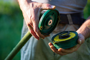 Lawn mower pulls the line out of the trimmer coil - maintenance of garden tools, close up trimmer...